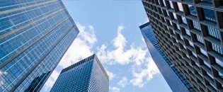 Vista hacia la cima de varios edificios de oficinas con el cielo parcialmente nublado