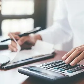 Persona estudiando algunos reportes financieros con ayuda de una calculadora